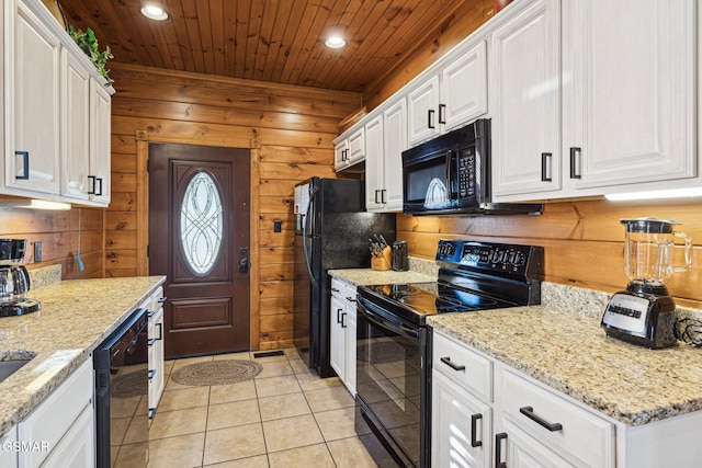 kitchen featuring white cabinets, black appliances, and wood walls