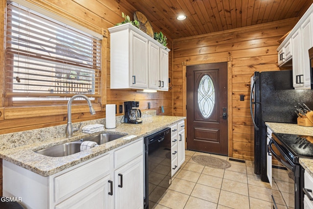 kitchen featuring sink, white cabinetry, black appliances, and wooden walls