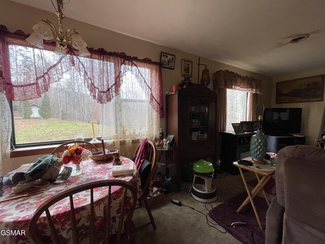 carpeted dining space featuring a notable chandelier