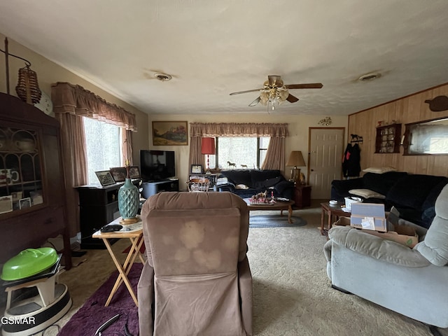 living room featuring carpet, a wealth of natural light, ceiling fan, and wooden walls