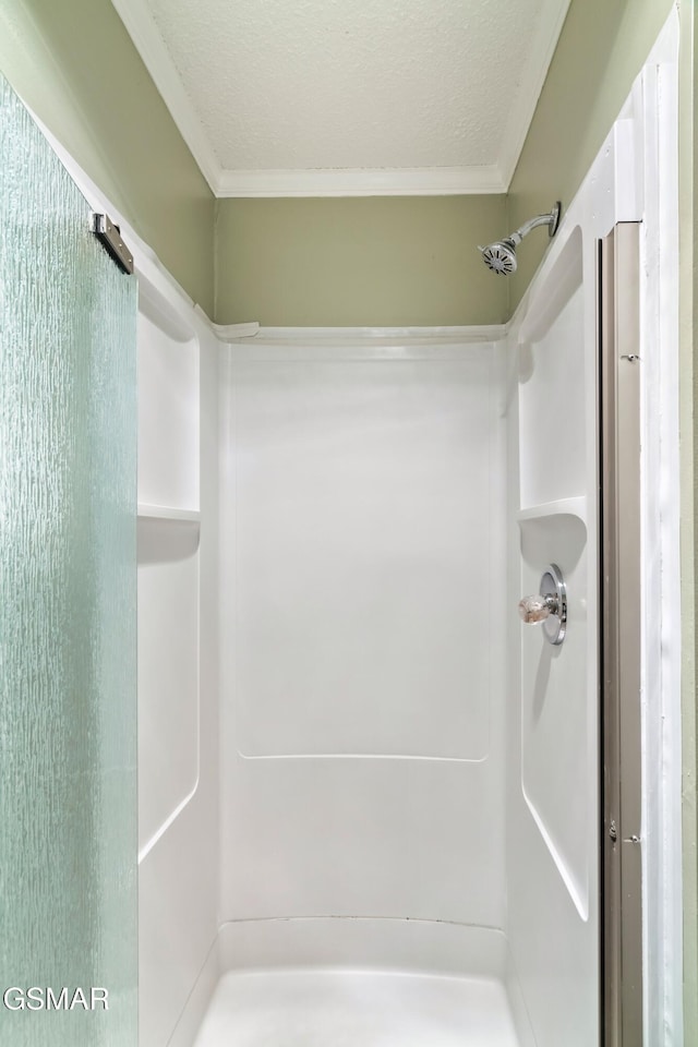 bathroom with a shower, ornamental molding, and a textured ceiling