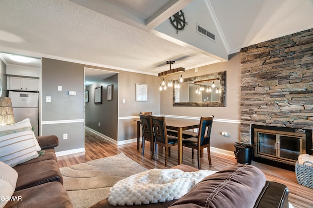 living room featuring a fireplace, light hardwood / wood-style floors, vaulted ceiling, and crown molding