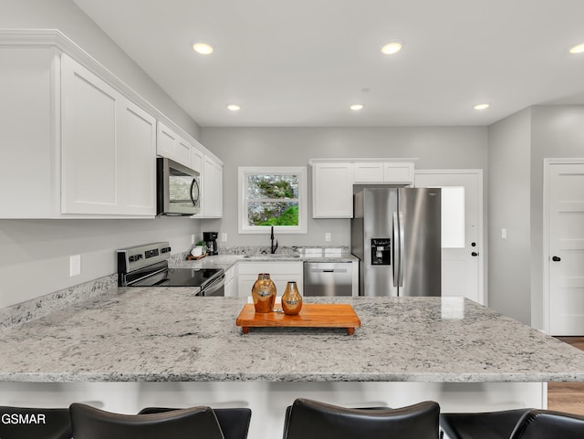 3141 Teaster Ln Unit 1, Pigeon Forge, TN 37863 - kitchen featuring appliances with stainless steel finishes, a peninsula, a kitchen breakfast bar, white cabinetry, and recessed lighting
