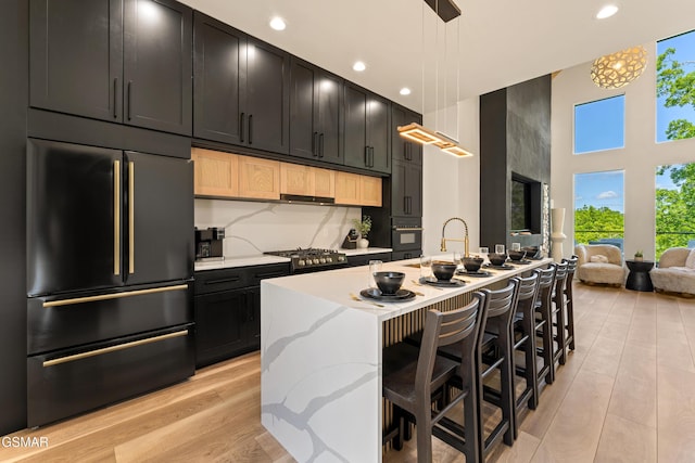 1163 Reedmont Way, Sevierville, TN 37876 - kitchen with paneled refrigerator, a towering ceiling, dark cabinetry, light wood-style floors, and oven