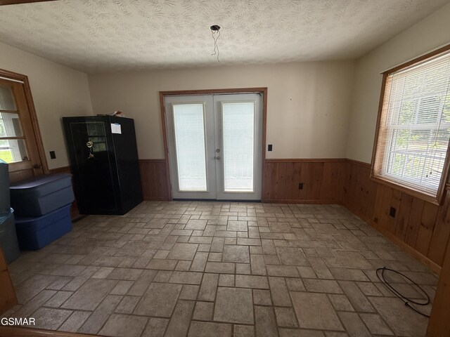 3380 Grassy Fork Rd, Hartford, TN 37753 - unfurnished dining area featuring a wainscoted wall, brick patterned floors, wooden walls, french doors, and a textured ceiling