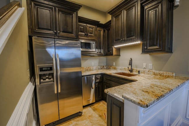 kitchen with dark brown cabinetry, light stone counters, sink, and appliances with stainless steel finishes