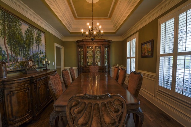 dining space featuring a chandelier, dark hardwood / wood-style floors, a raised ceiling, and ornamental molding