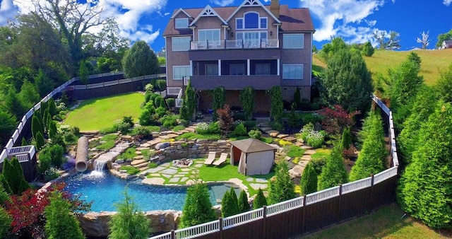 rear view of property with a lawn, a balcony, and a shed