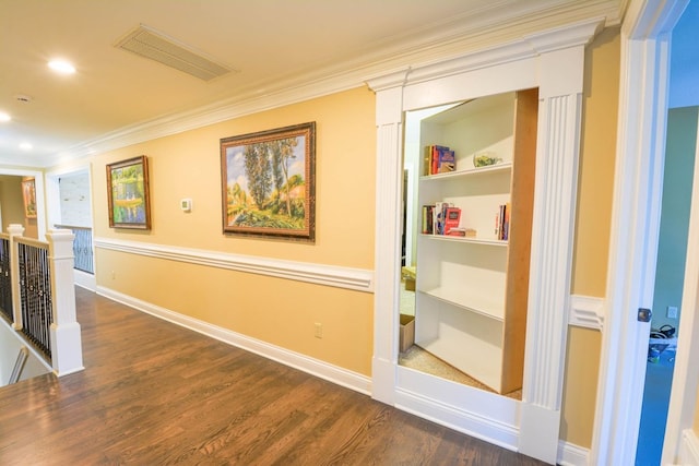 corridor with built in shelves, dark hardwood / wood-style flooring, and ornamental molding