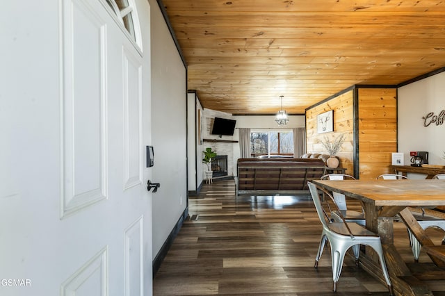 dining area featuring dark wood-style floors, wooden ceiling, and a fireplace