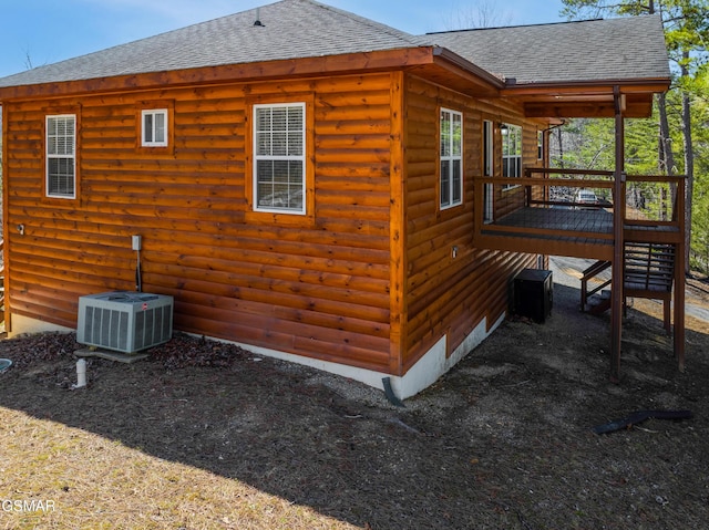 view of property exterior with roof with shingles, a wooden deck, and central AC unit