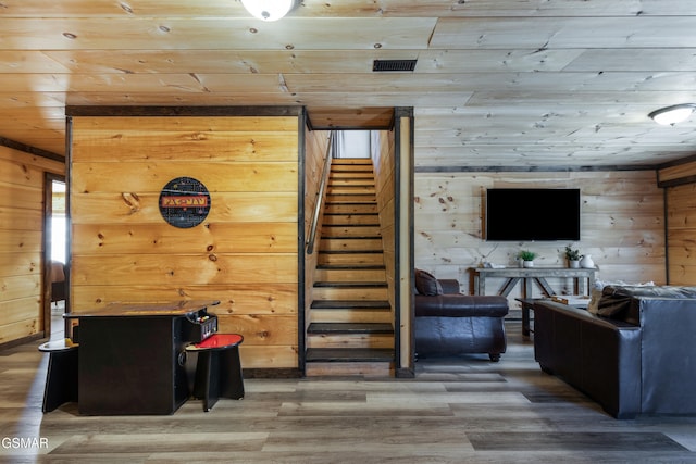 living area featuring wood walls, wood ceiling, stairway, and wood finished floors