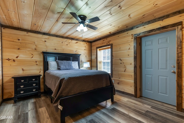 bedroom with ceiling fan, wood walls, dark wood finished floors, and wood ceiling