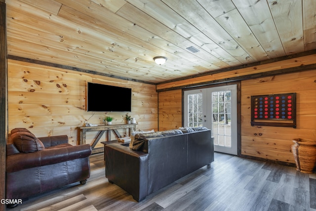 living room with wood walls, wood finished floors, visible vents, wood ceiling, and french doors