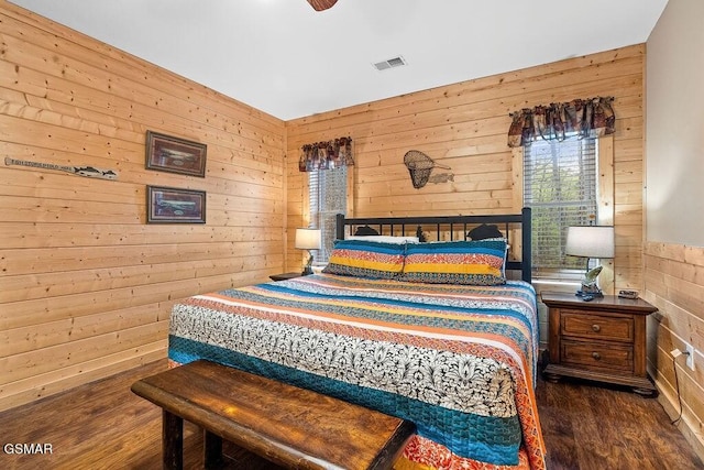 bedroom featuring ceiling fan, dark wood-type flooring, and wooden walls