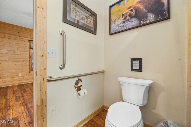 bathroom featuring wood walls, wood-type flooring, and toilet