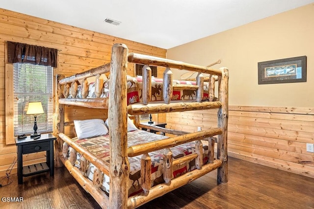 bedroom with hardwood / wood-style floors and wooden walls