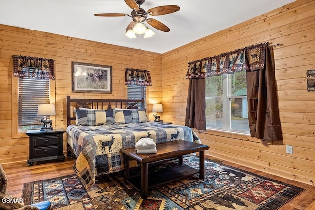 bedroom with wood-type flooring, ceiling fan, and wooden walls