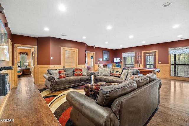 living room with a wealth of natural light, light hardwood / wood-style flooring, wood walls, and billiards