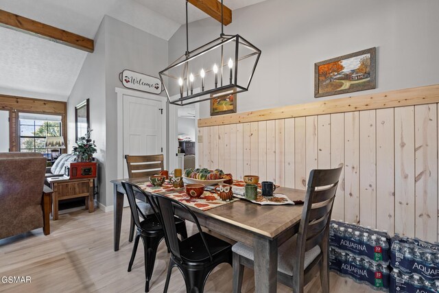 3225 Laurelwood Ave, Sevierville, TN 37862 - dining room featuring beam ceiling, light wood-type flooring, a chandelier, wooden walls, and high vaulted ceiling