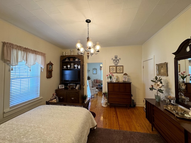 bedroom featuring a chandelier, hardwood / wood-style floors, and crown molding