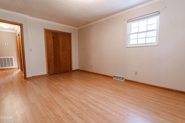 unfurnished bedroom featuring a textured ceiling, light hardwood / wood-style floors, crown molding, and a closet