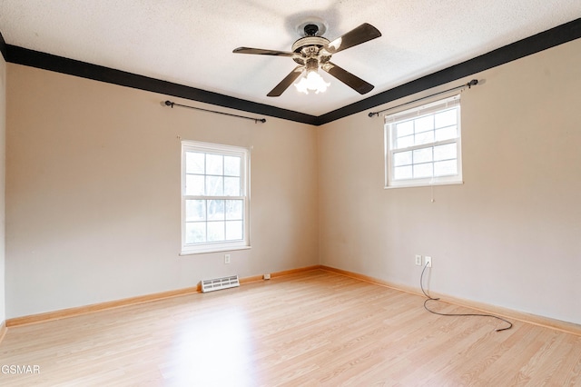 empty room featuring a textured ceiling, light hardwood / wood-style flooring, and ceiling fan