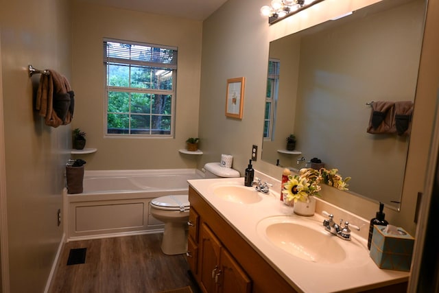 bathroom featuring a tub, vanity, wood-type flooring, and toilet