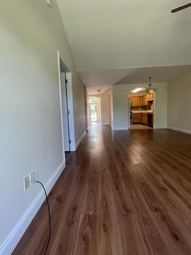 unfurnished living room with ceiling fan and dark wood-type flooring