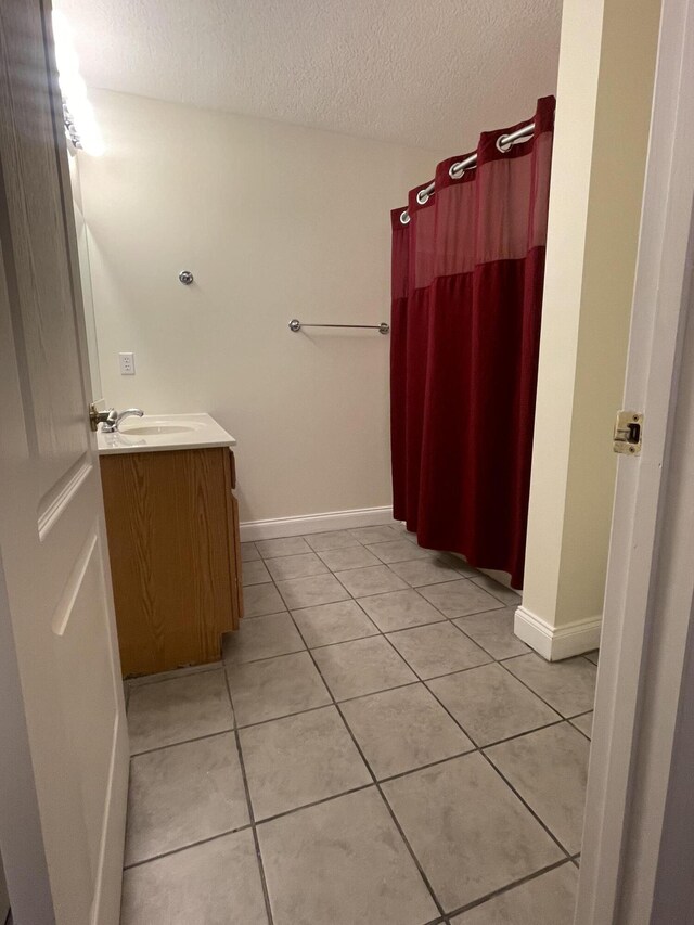 bathroom with tile patterned flooring, a textured ceiling, and vanity