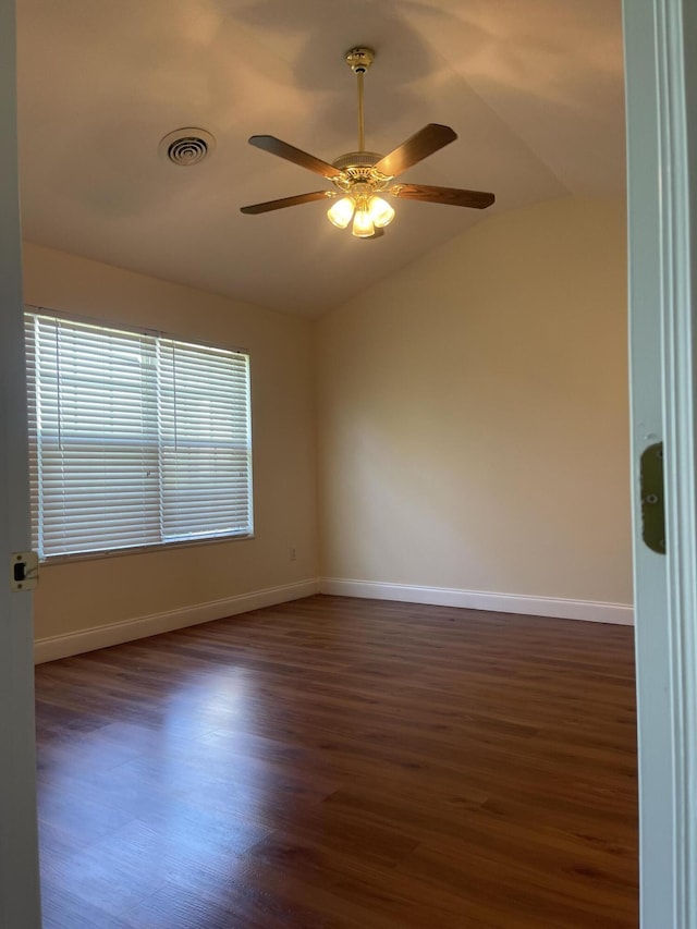 spare room featuring dark hardwood / wood-style floors, ceiling fan, and vaulted ceiling