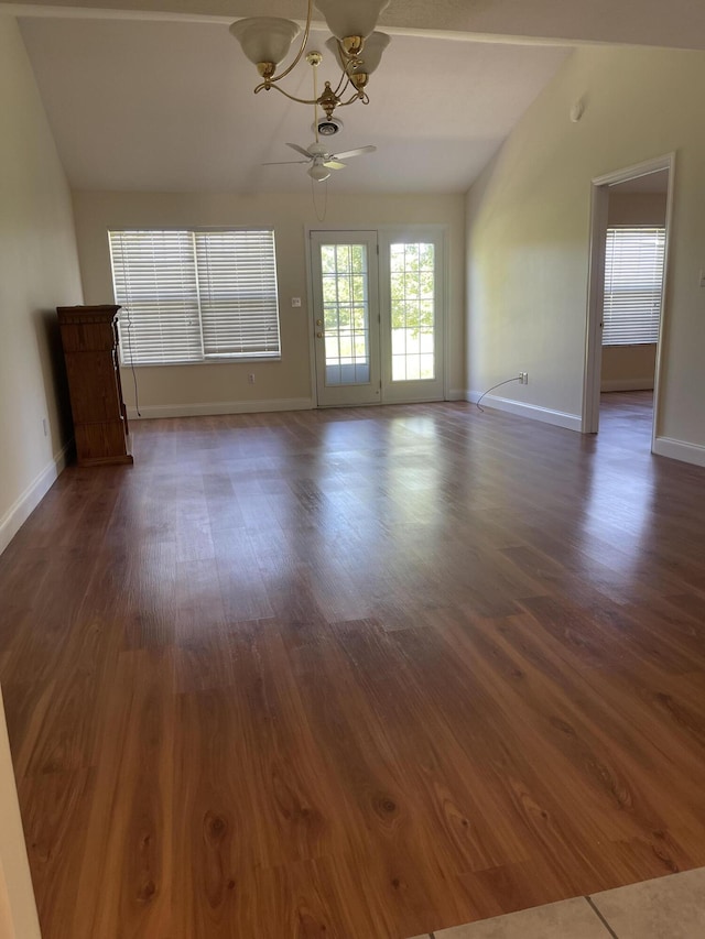 unfurnished room with ceiling fan with notable chandelier, dark wood-type flooring, and vaulted ceiling