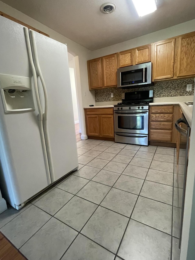 kitchen featuring appliances with stainless steel finishes, tasteful backsplash, and light tile patterned flooring