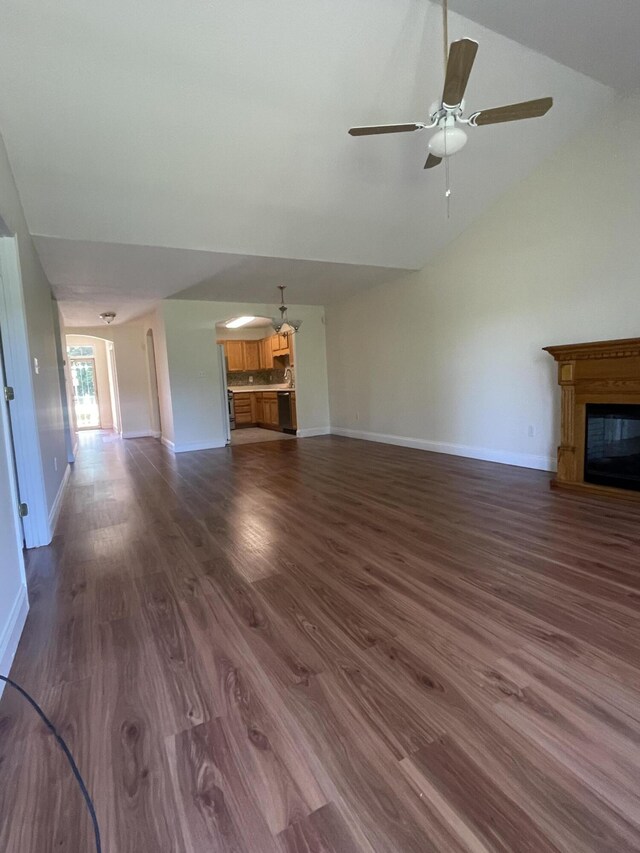 unfurnished living room with ceiling fan, dark wood-type flooring, and vaulted ceiling