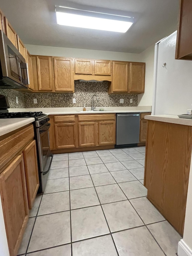 kitchen with light tile patterned flooring, stainless steel appliances, tasteful backsplash, and sink