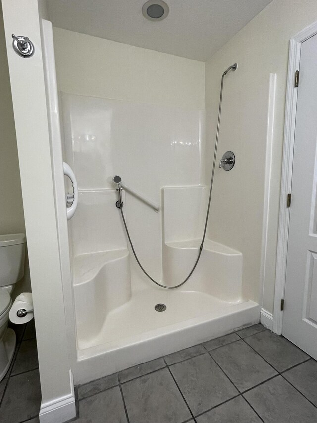 bathroom with a shower, tile patterned flooring, and toilet