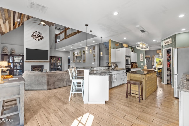 kitchen with a peninsula, a fireplace, a breakfast bar area, and visible vents