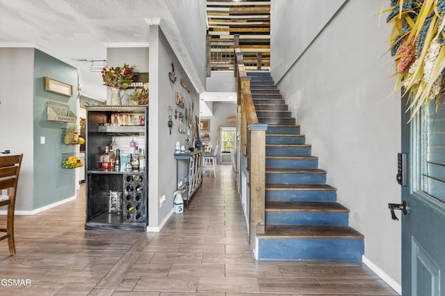 stairs featuring a dry bar, baseboards, and wood tiled floor