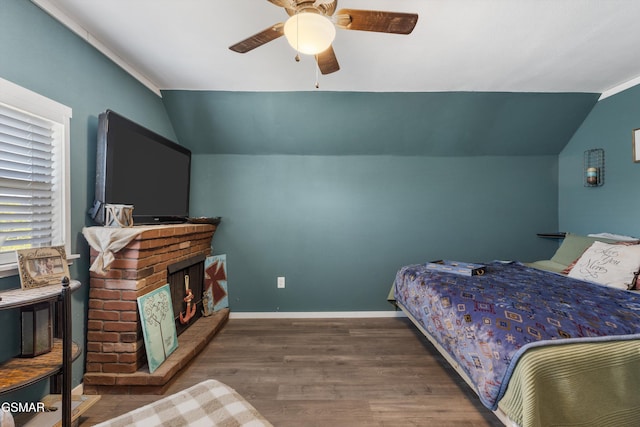 bedroom featuring a brick fireplace, baseboards, wood finished floors, and lofted ceiling