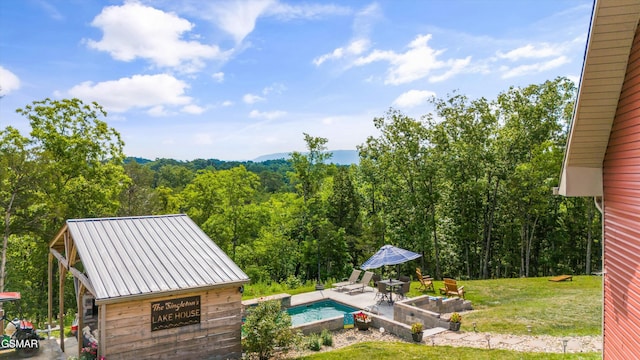 pool with a yard, a patio area, and a wooded view