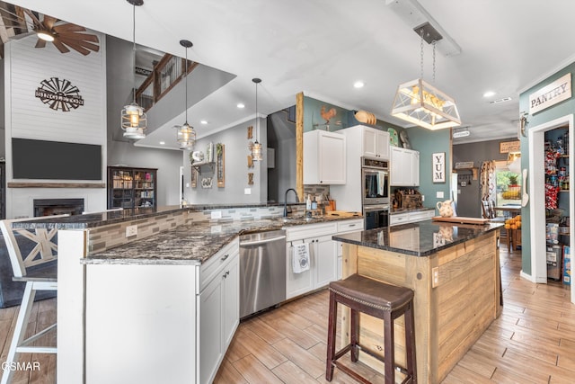 kitchen featuring a breakfast bar, a peninsula, light wood-style flooring, appliances with stainless steel finishes, and a sink