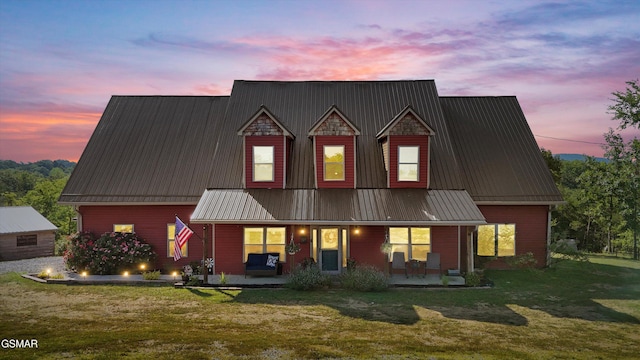 back of property at dusk with a patio, a yard, and metal roof