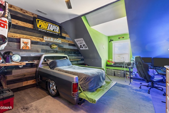 bedroom with wood walls, wood finished floors, and visible vents