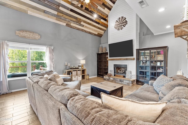 living area featuring a stone fireplace, a ceiling fan, visible vents, high vaulted ceiling, and wood finished floors