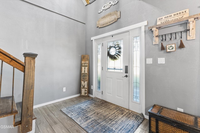 foyer entrance featuring wood finished floors, a high ceiling, and baseboards