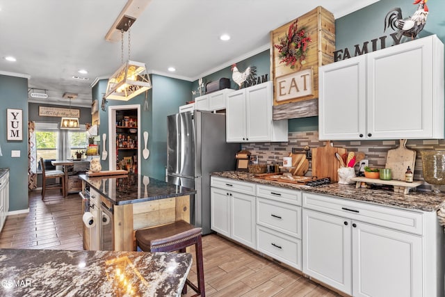 kitchen featuring tasteful backsplash, freestanding refrigerator, and ornamental molding