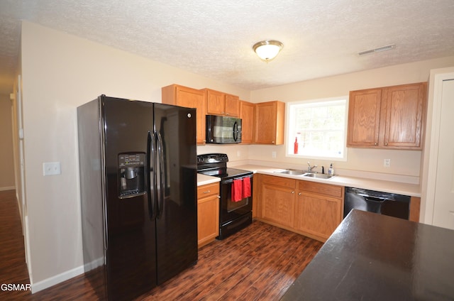 kitchen featuring visible vents, black appliances, dark wood finished floors, a textured ceiling, and a sink