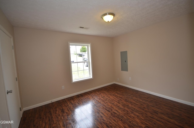 empty room featuring baseboards, visible vents, dark wood finished floors, electric panel, and a textured ceiling