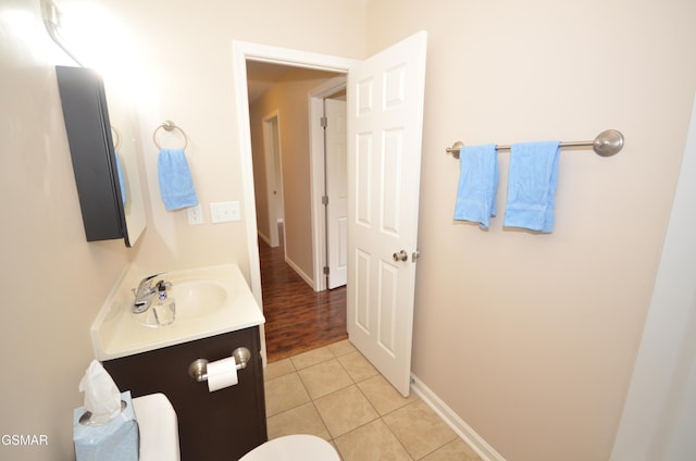 half bath with vanity, tile patterned floors, and baseboards