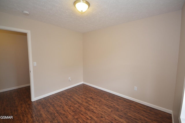 spare room with baseboards, a textured ceiling, and dark wood finished floors